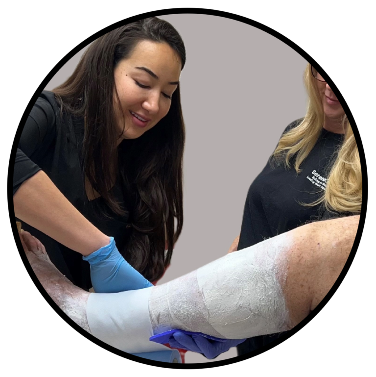 A physician and an assistant help wrap the leg of a patient with diabetic leg and foot ulcers.