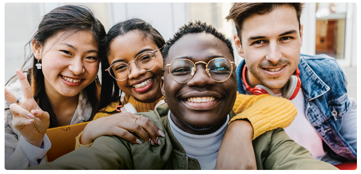 A group of four teen friends are smiling for a photo.